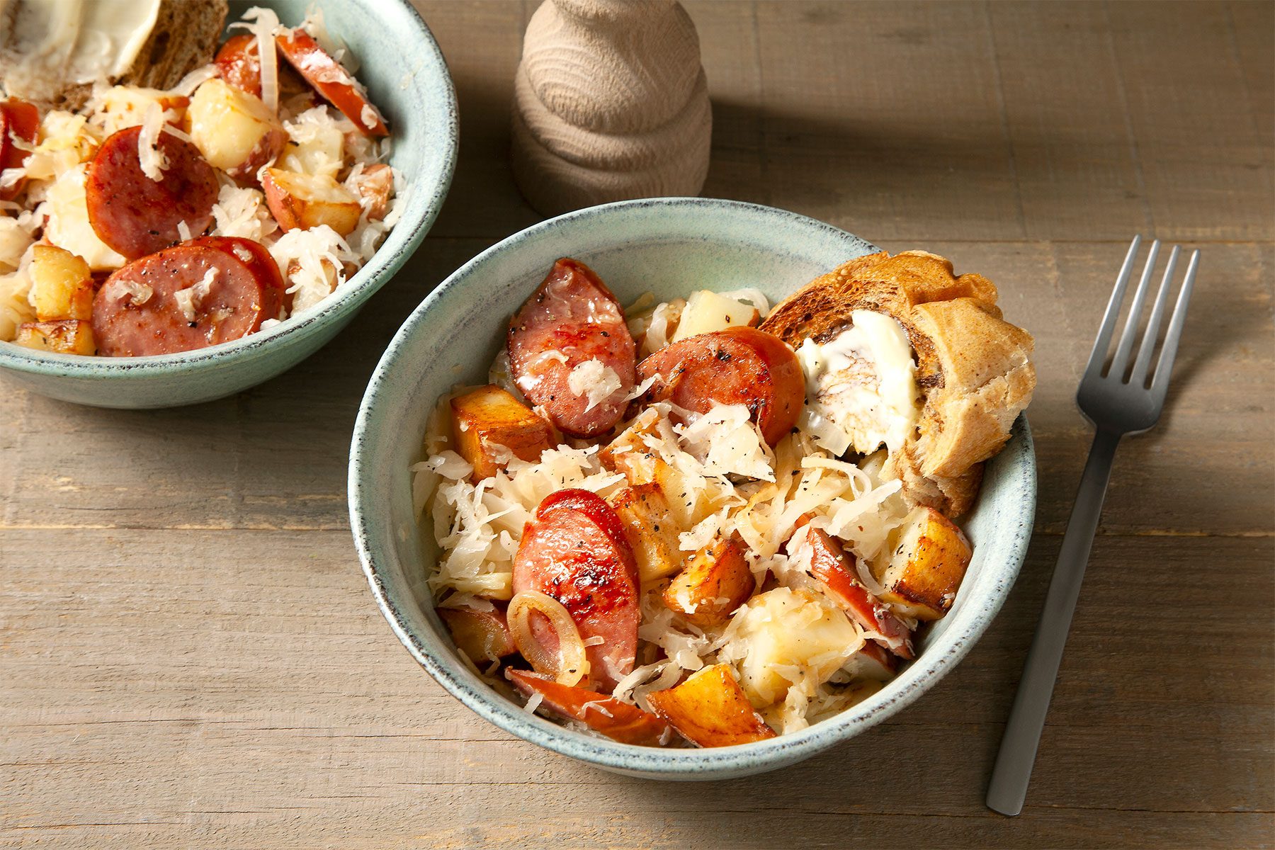 Sausage And Sauerkraut in bowls with fork on side on wooden base