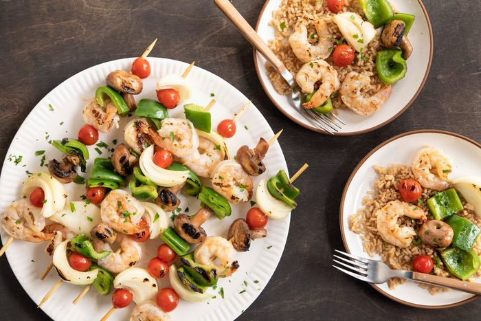Shrimp Kabobs served in plates with brown rice on a wooden table