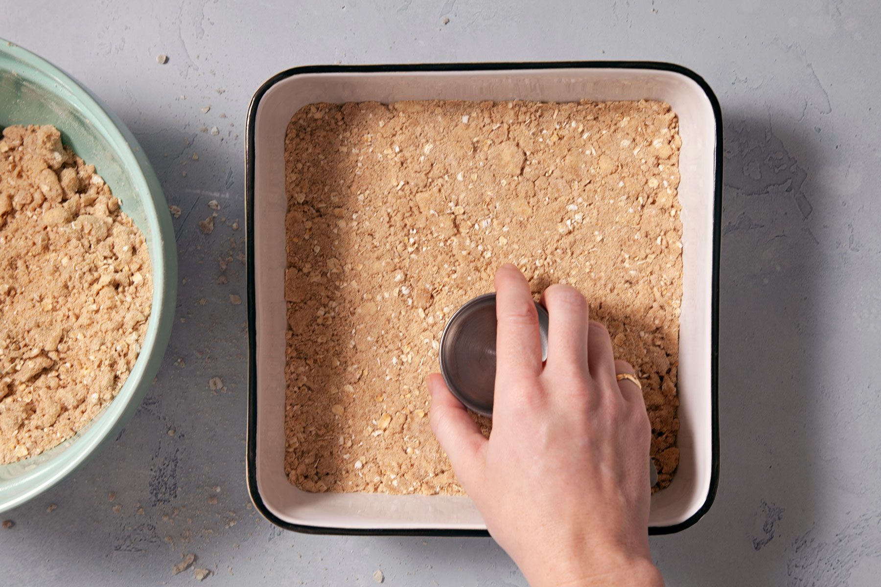 Pressing the mixture with a cup in a baking pan