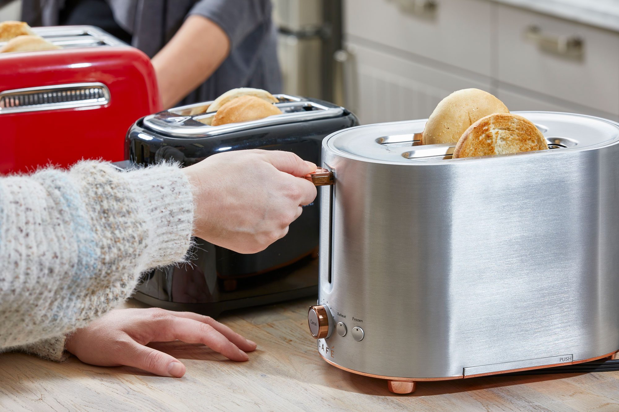 A Woman Using Café Express Toaster on Wooden Kitchen Countertop