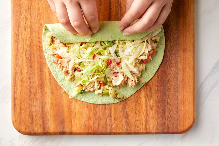 A person rolling the tuna salad tortillas