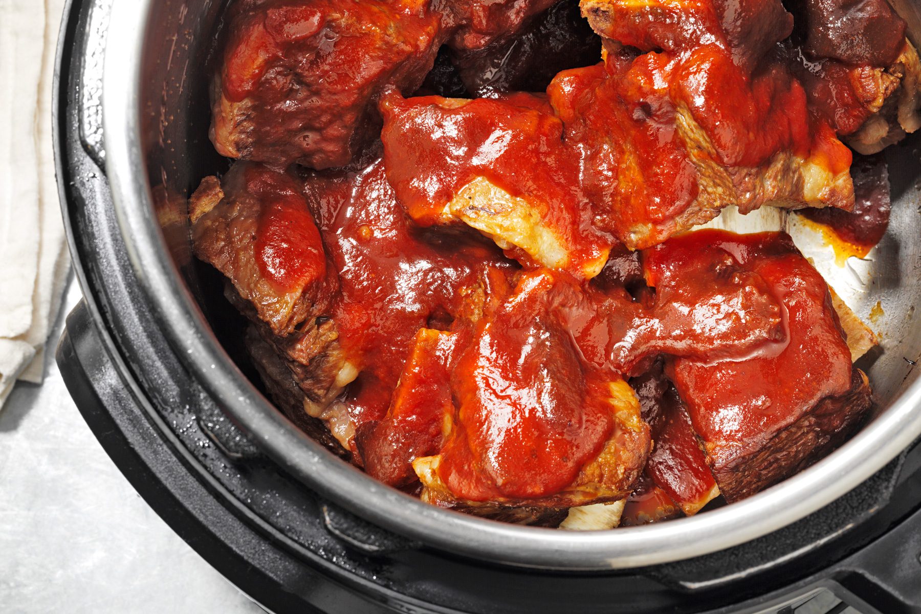 A pressure cooker filled with barbecued beef ribs covered in sauce