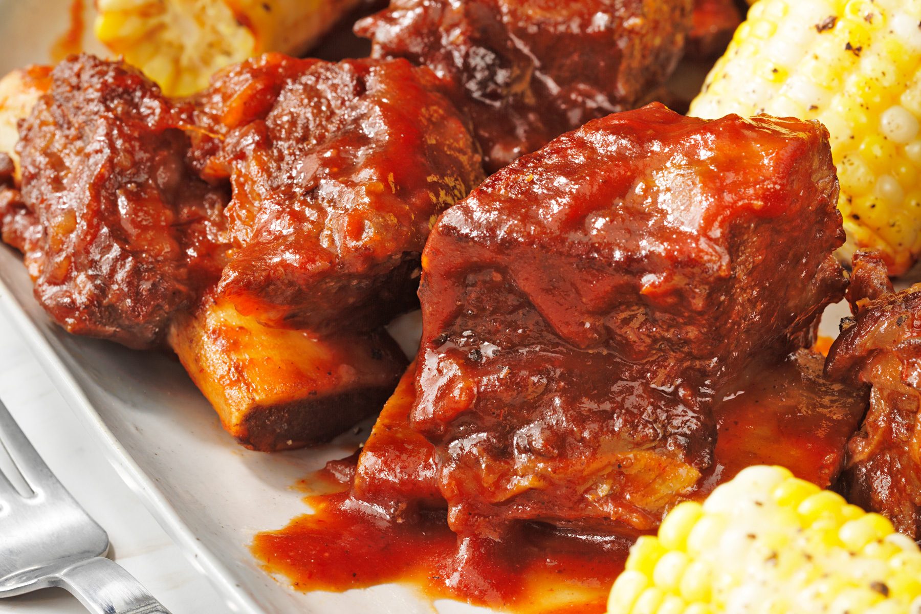 A plate of pressure cooker barbecued beef ribs served with corn on the cob