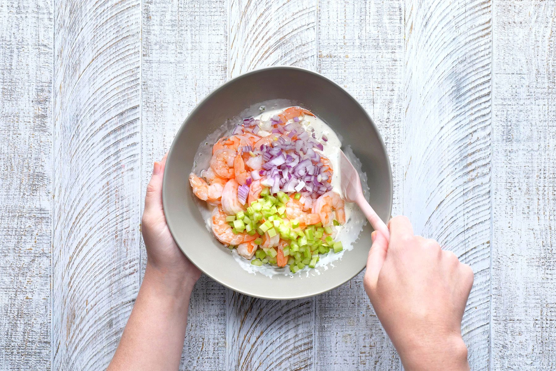 overhead shot of mixing shrimps in the ingredients in a large bowl