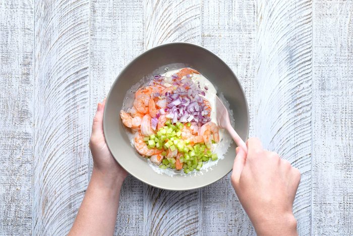 overhead shot of mixing shrimps in the ingredients in a large bowl