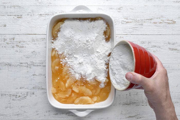 overhead shot of cake mix spreaded over apple pie filling in a baking dish
