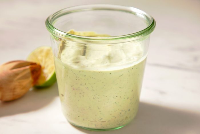 Table view shot of Avocado-Lime Ranch Dressing; in a glass jar; half cut lemon; marble background;
