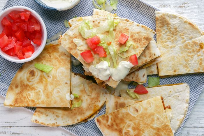 overhead shot of cheeseburger quesadillas garnished shredded lettuce and chopped tomatoes