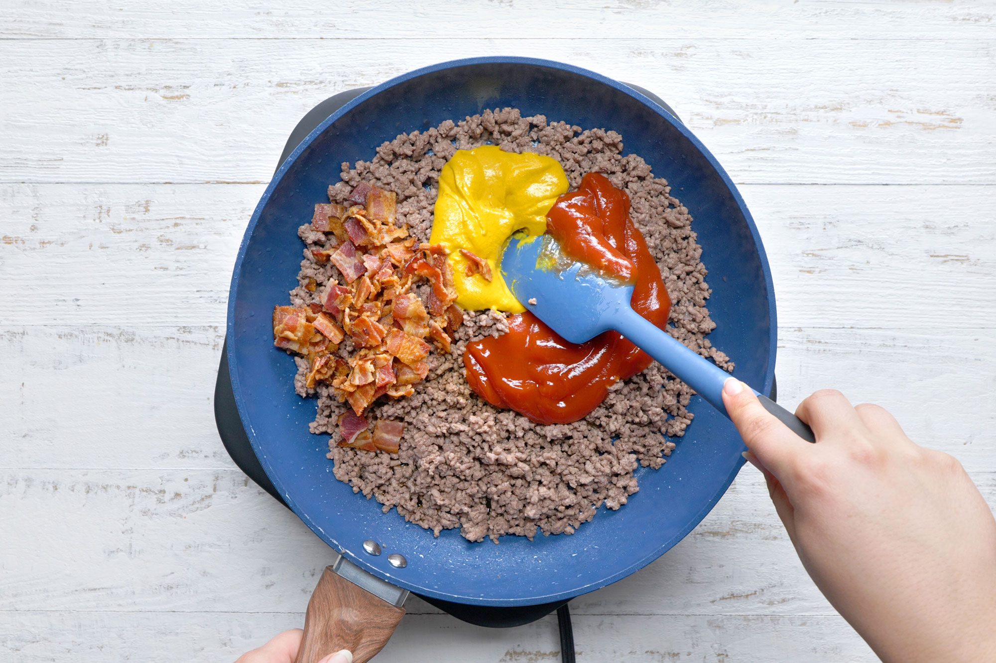 overhead shot of mustard, ketchup added in the cooked beef mix