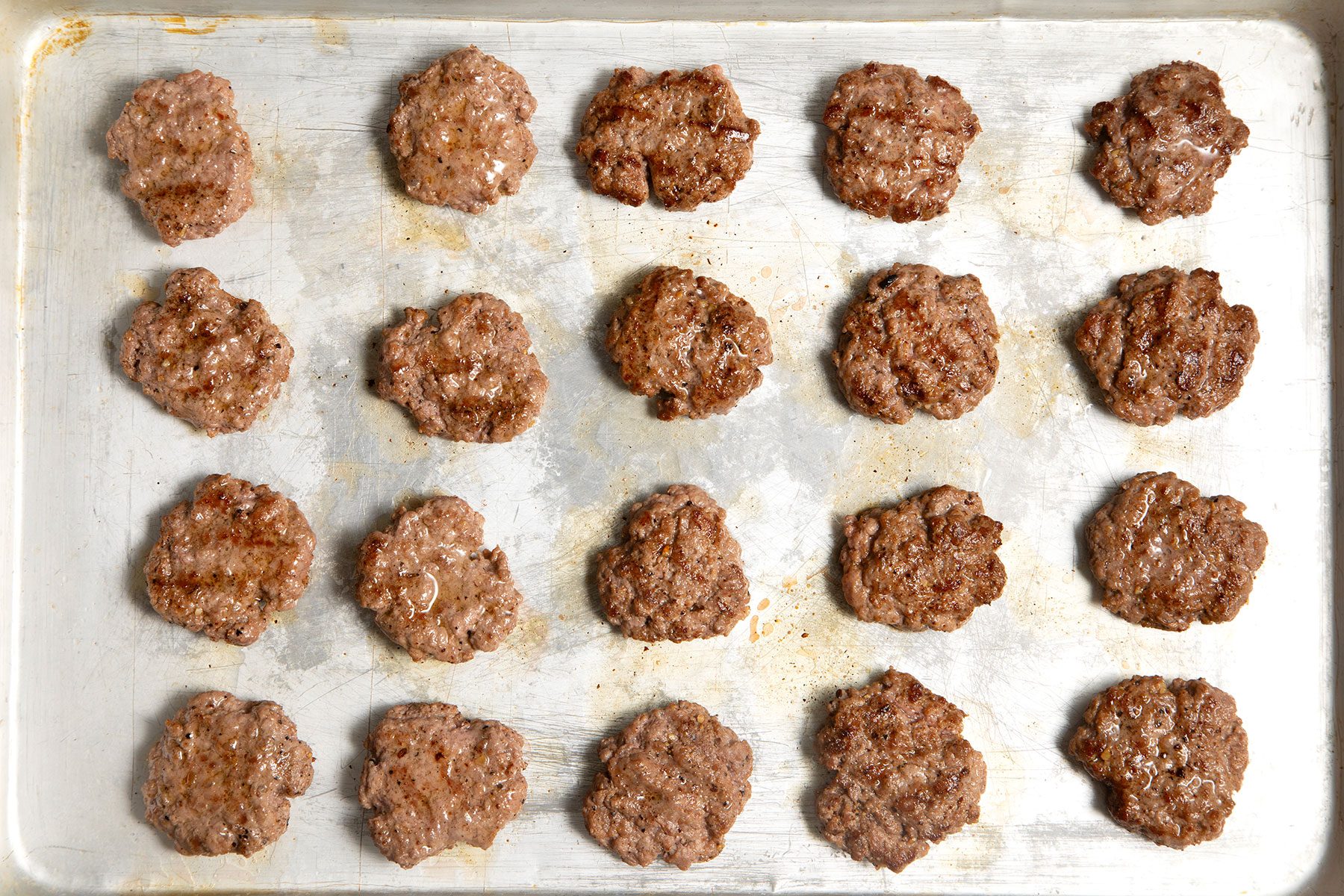 overhead shot; grilled burger patties placed on a frying dish;