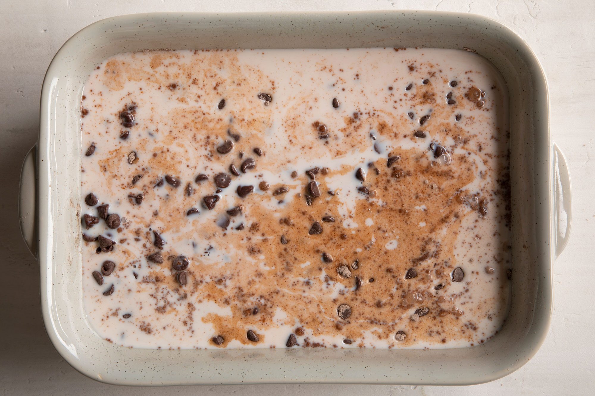 milk, chocolate chips and dry cake mix in a rectangular baking dish