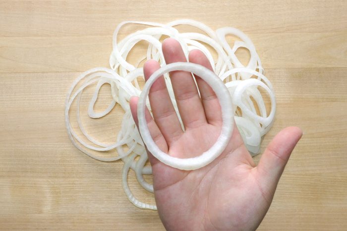 overhead shot; wooden background; onions rings on base; onion ring on hand;