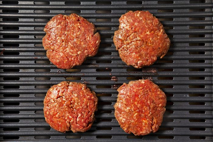 overhead shot; black background; grilling burger patties on griller;