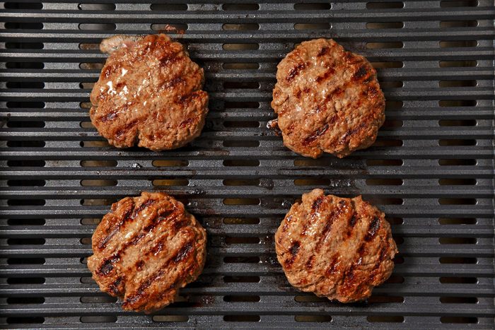 overhead shot; black background; grilling burger patties on griller;