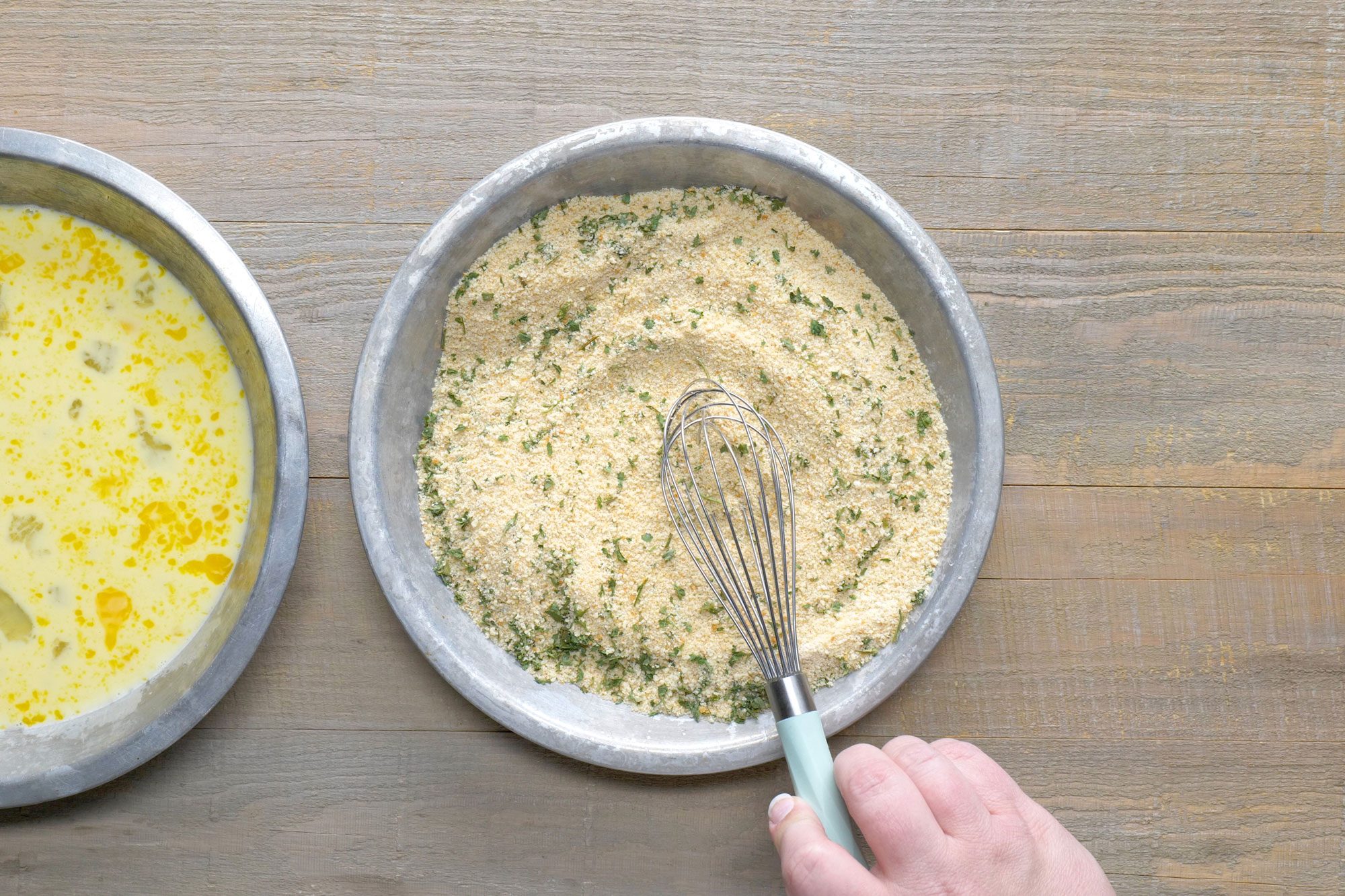 Overhead shot of combined bread crumbs; parsley and garlic powder in a shallow bowl; wooden background;