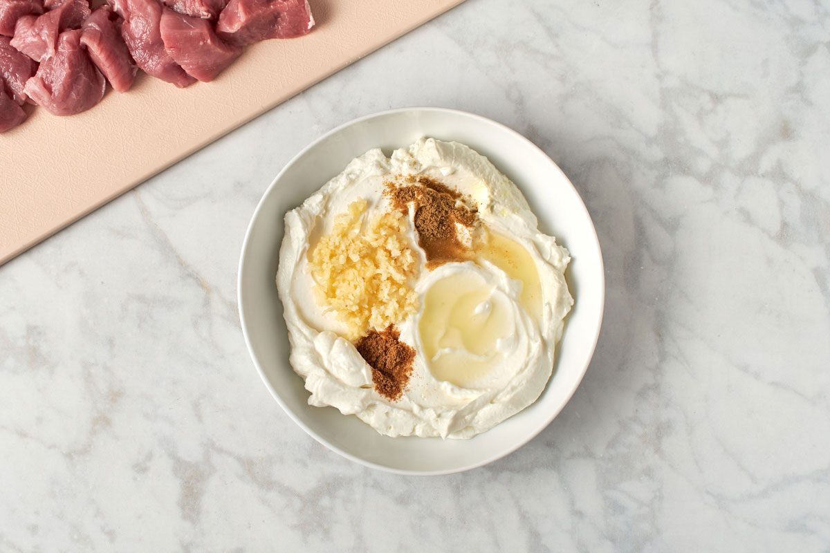 Marinade ingredients in a bowl with pork pieces nearby
