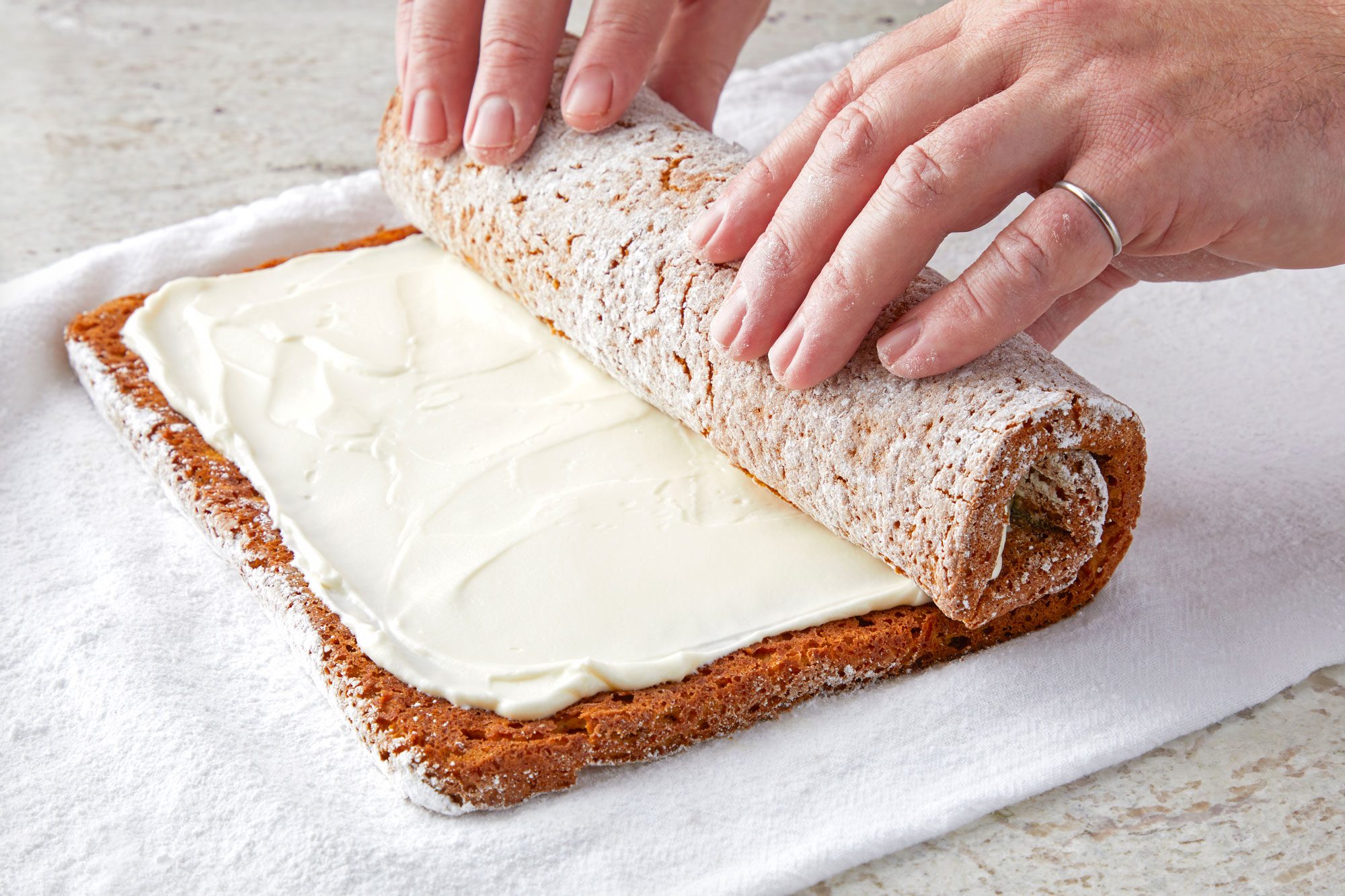 3/4th shot; white background; Rolling up the cake again without towel;