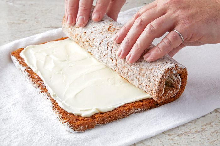3/4th shot; white background; Rolling up the cake again without towel;