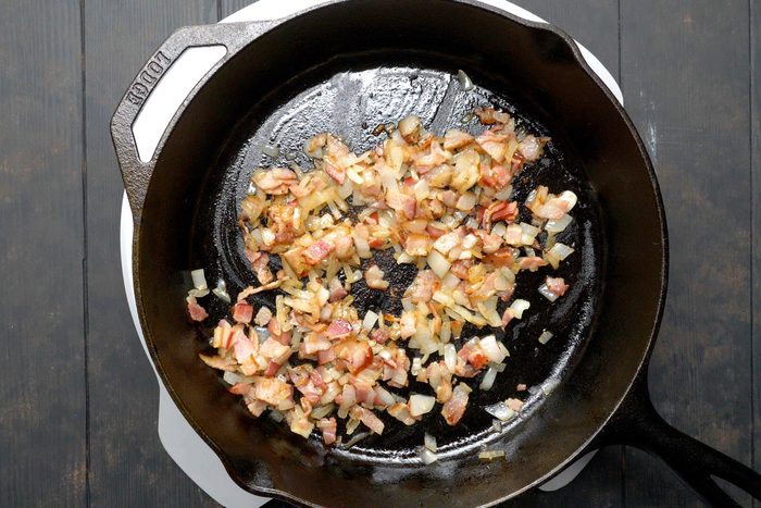 Bacon bits and onions frying in a large skillet