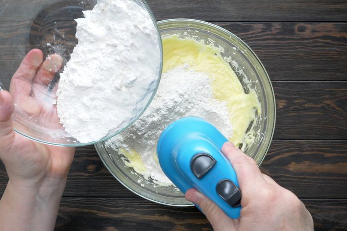 A person is mixing the dry ingredients into the cream mixture.