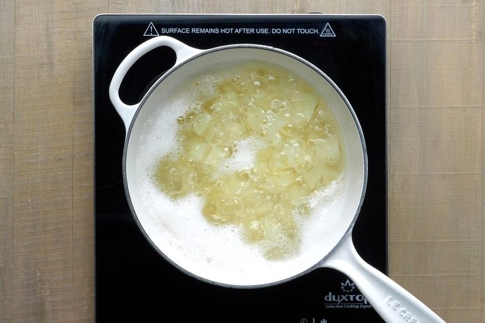 Potato cubes are boiling in water in a large saucepan.