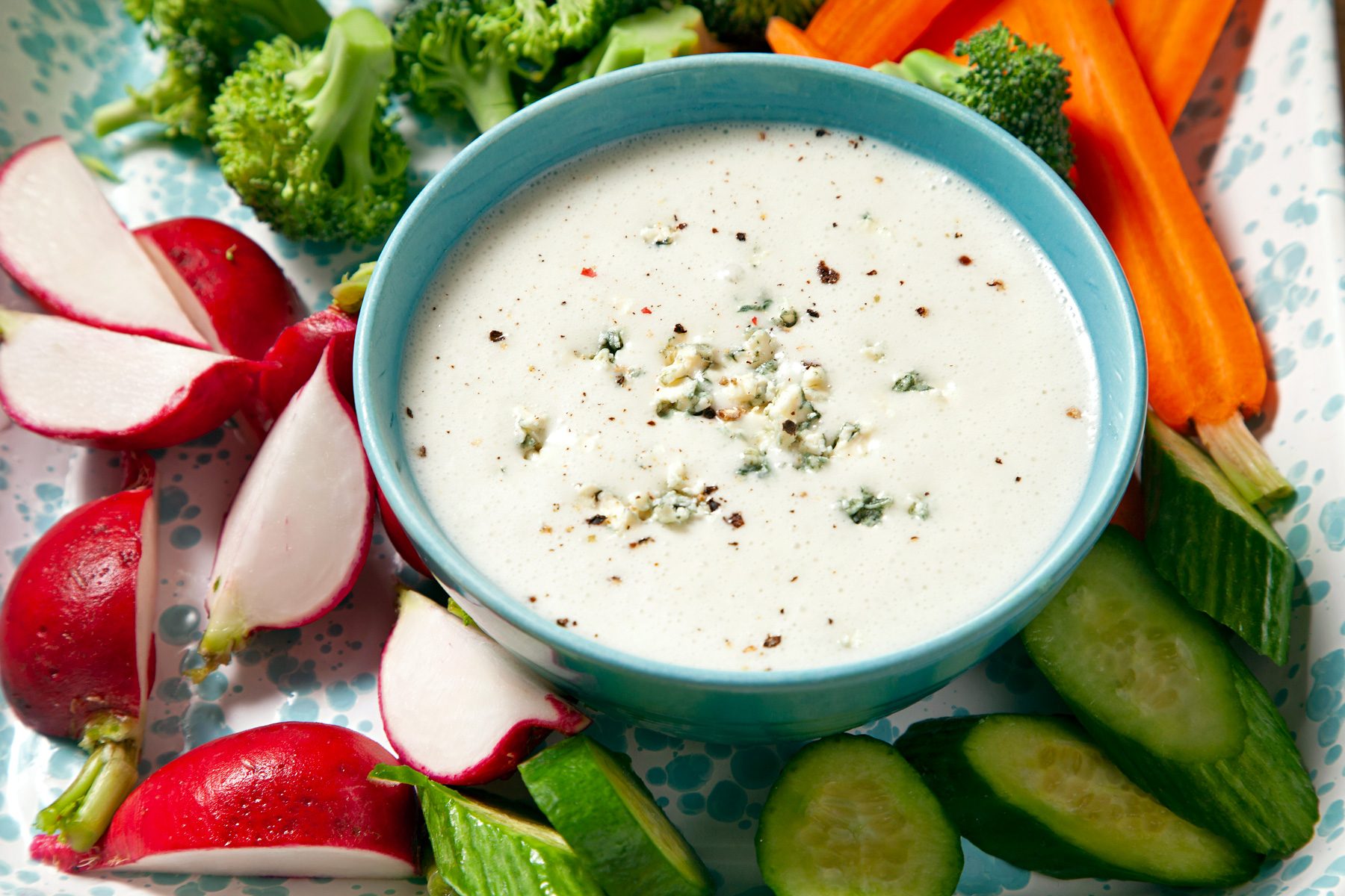 Blue Cheese Vinaigrette in a bowl with cucumber, carrots and broccoli on the side