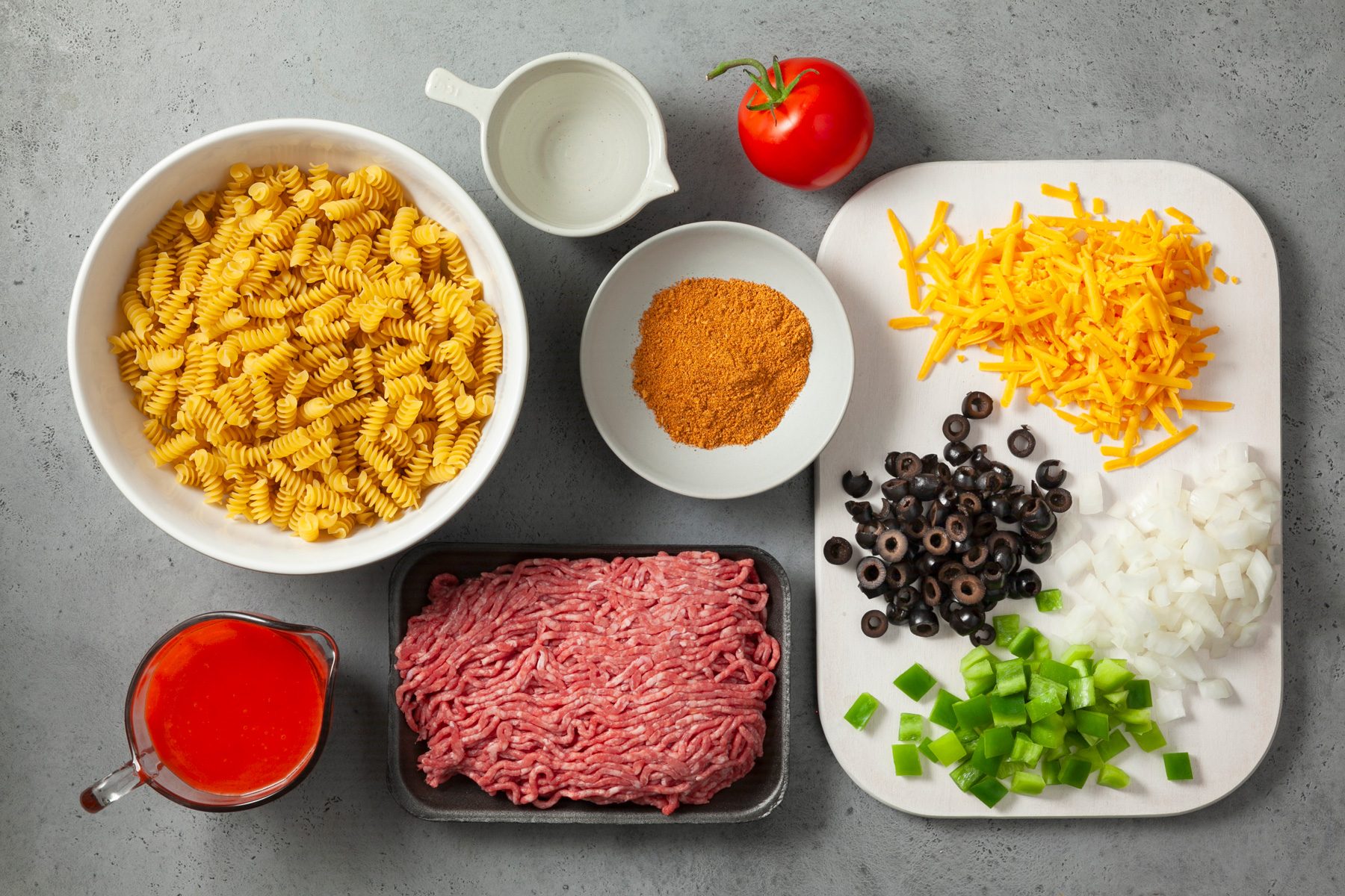Ingredients for Cowboy Pasta Salad including ground beef, olives, capsicum, oil, cheese, pasta