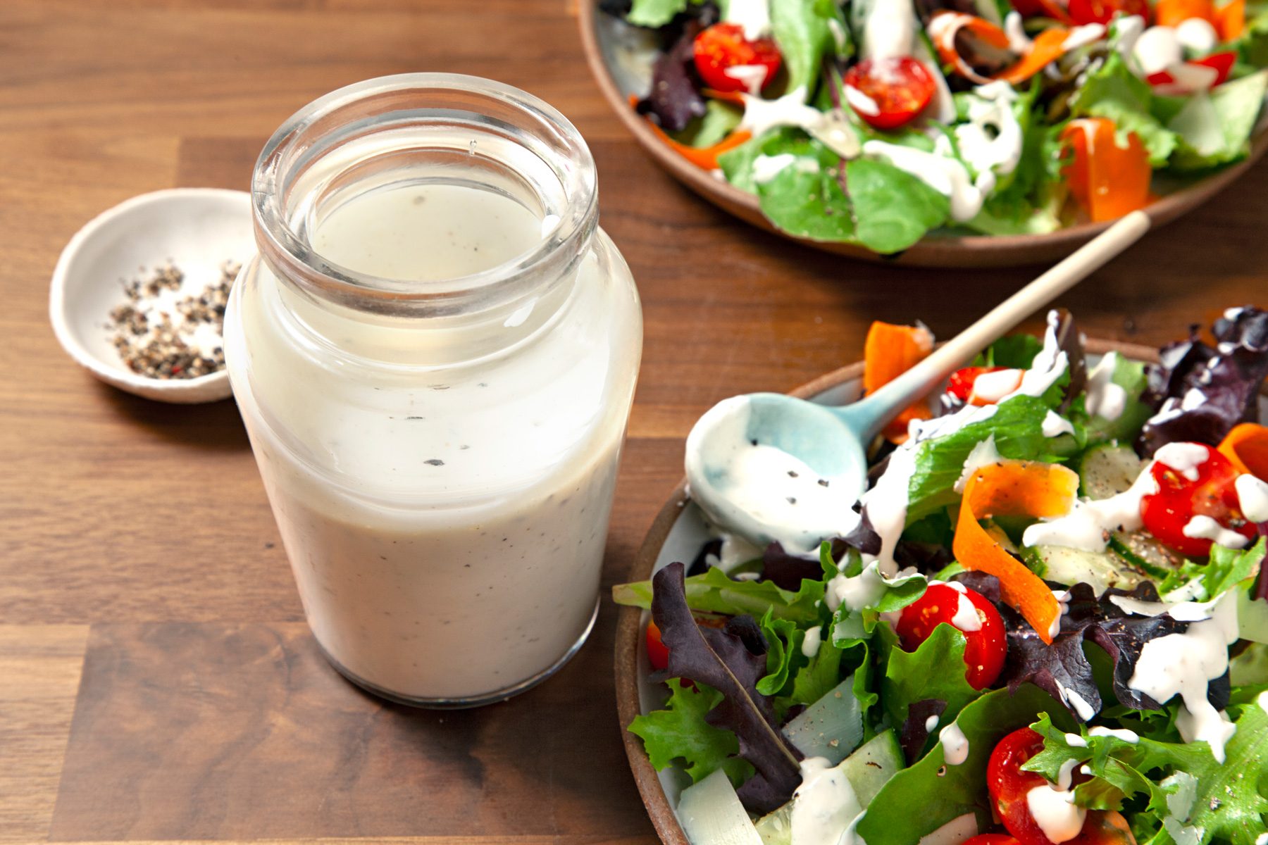 A Jar of Creamy Peppercorn Dressing on a wooden table