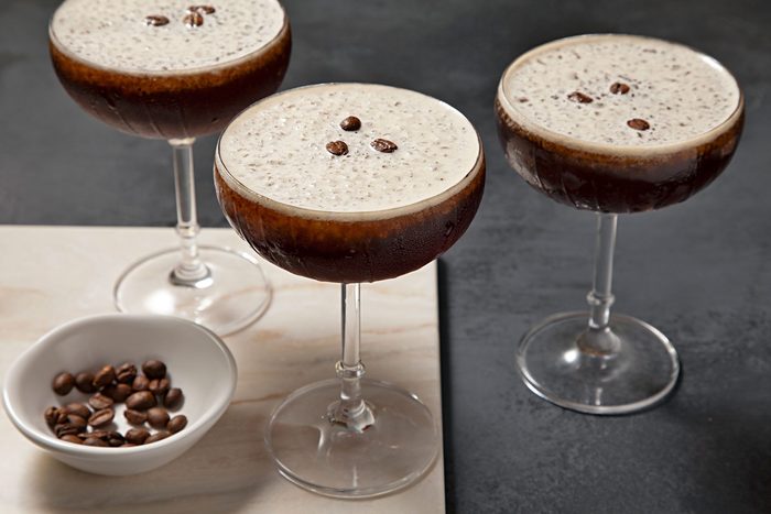 High angle view shot of Frozen Espresso Martini; in martini glasses; garnish with coffee beans; serve on wooden tray; coffee beans bowl; dark grey background;