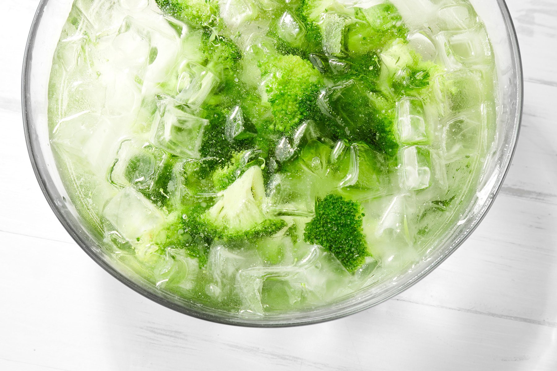 overhead shot; white background; ice bath broccoli in a large bowl;