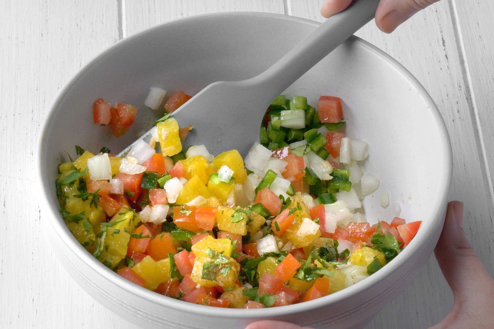 3/4th shot; white background; mixing all ingredients in a large white bowl;