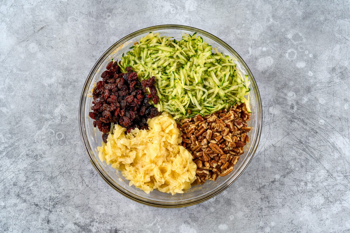 shredded zucchini, crushed pineapple, chopped nuts, and raisins in a bowl