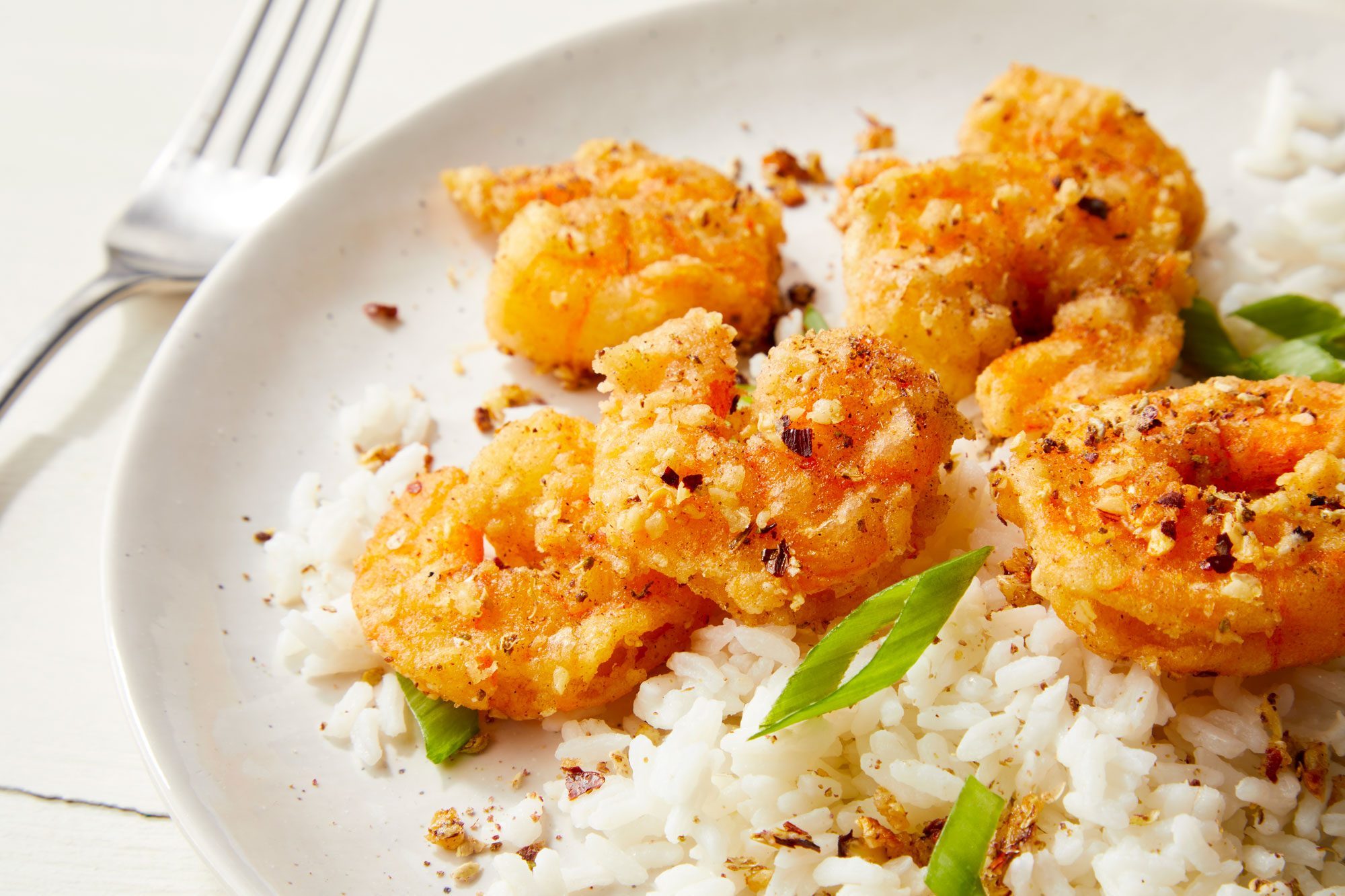 Salt and Ppper Shrimp served on plates with rice and sprinkle green onions over it
