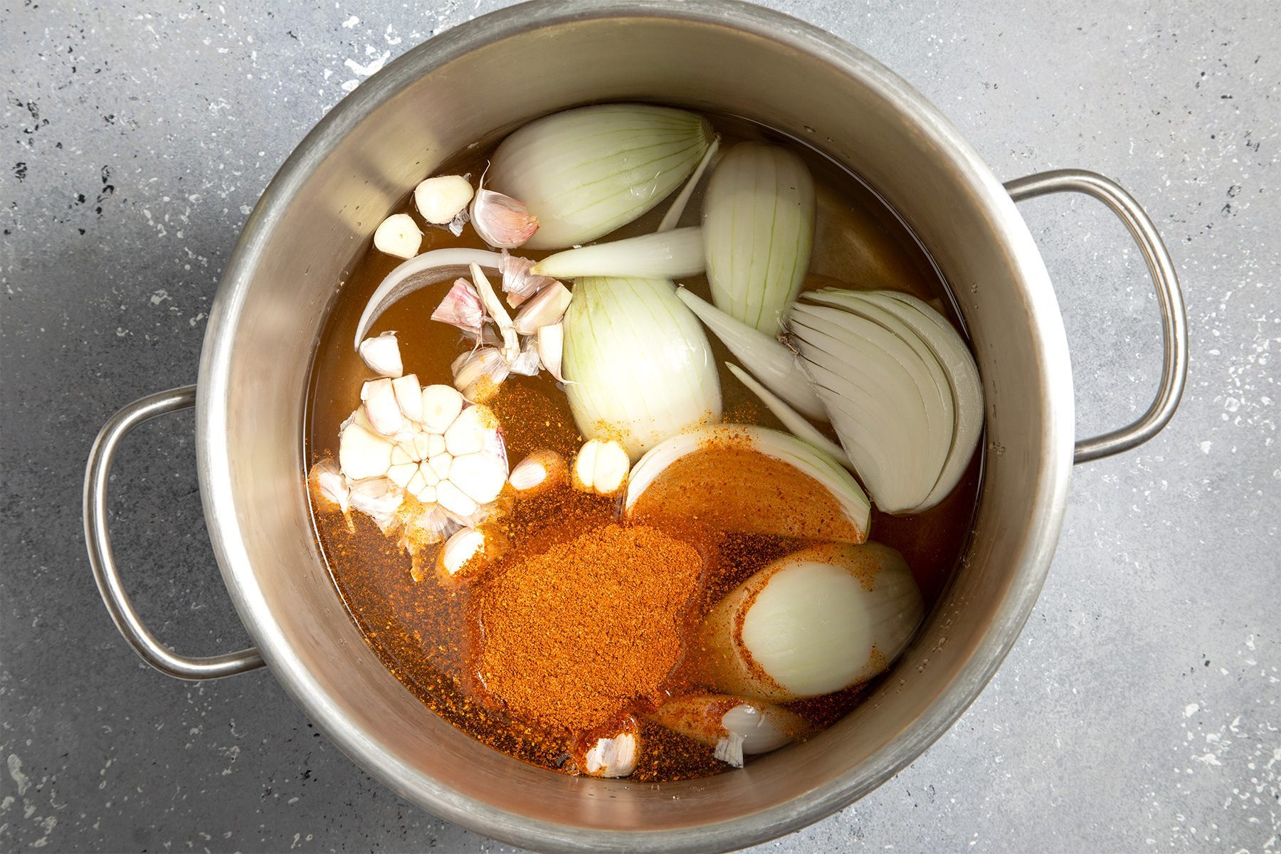overhead shot of water, onion, garlic and seafood seasoning in a stockpot; bring to a boil