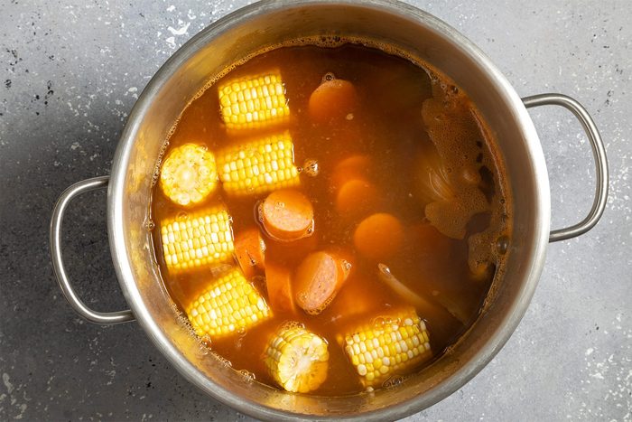 overhead shot of sweet corn and sausages added in the mix in a stockpot
