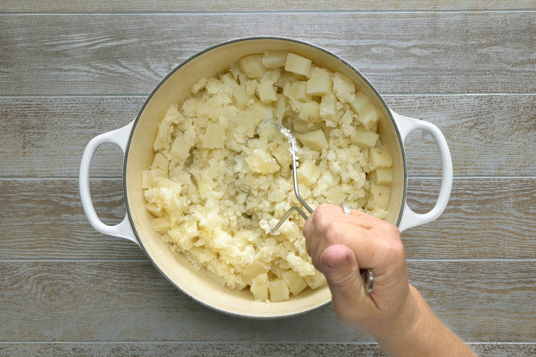 Using a potato masher, mash the potatoes
