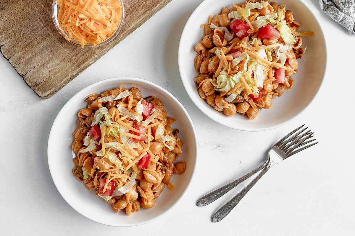 Taco Mac and Cheese in white bowls next to a wooden board