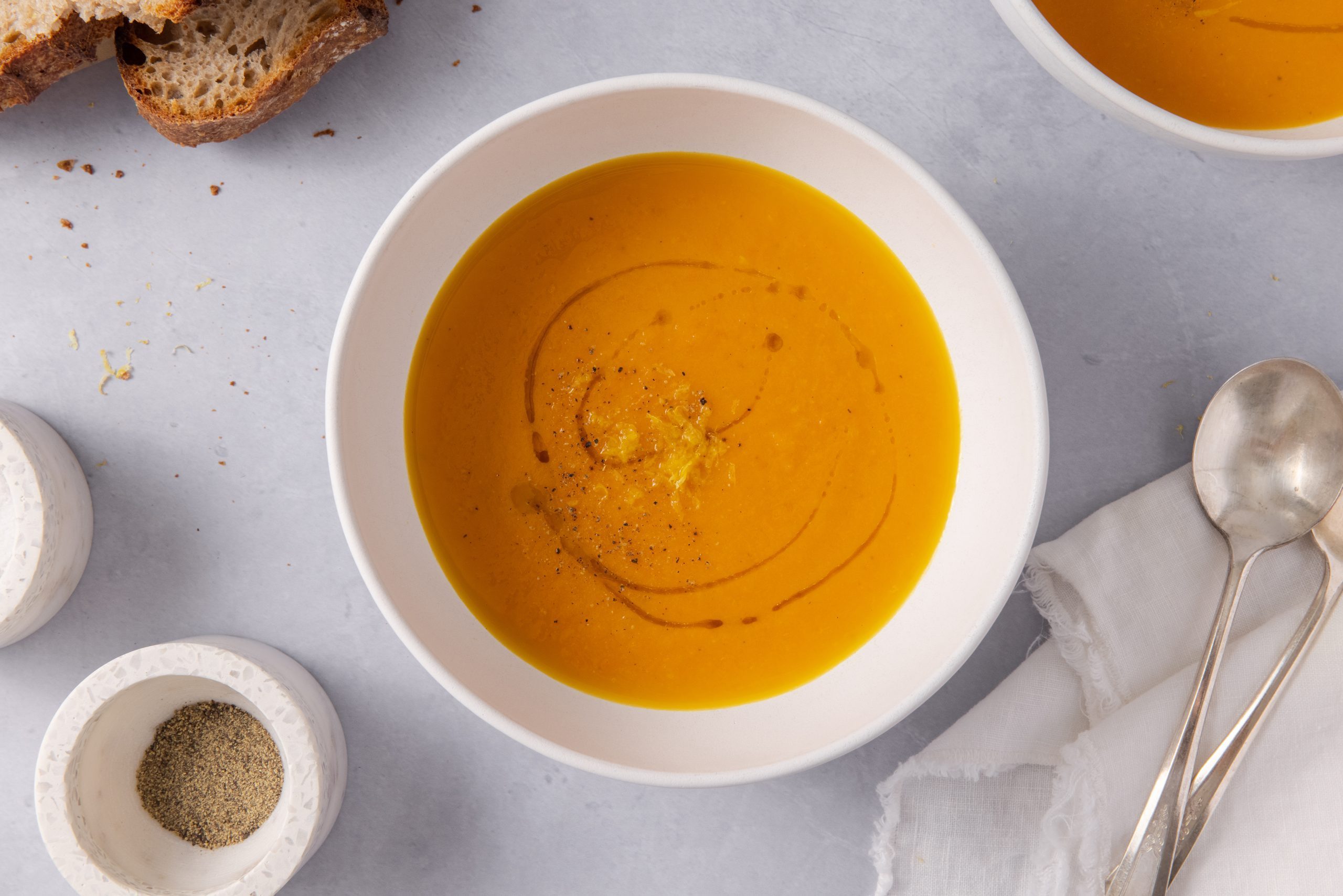 Soup served in a bowl with bread on the side.