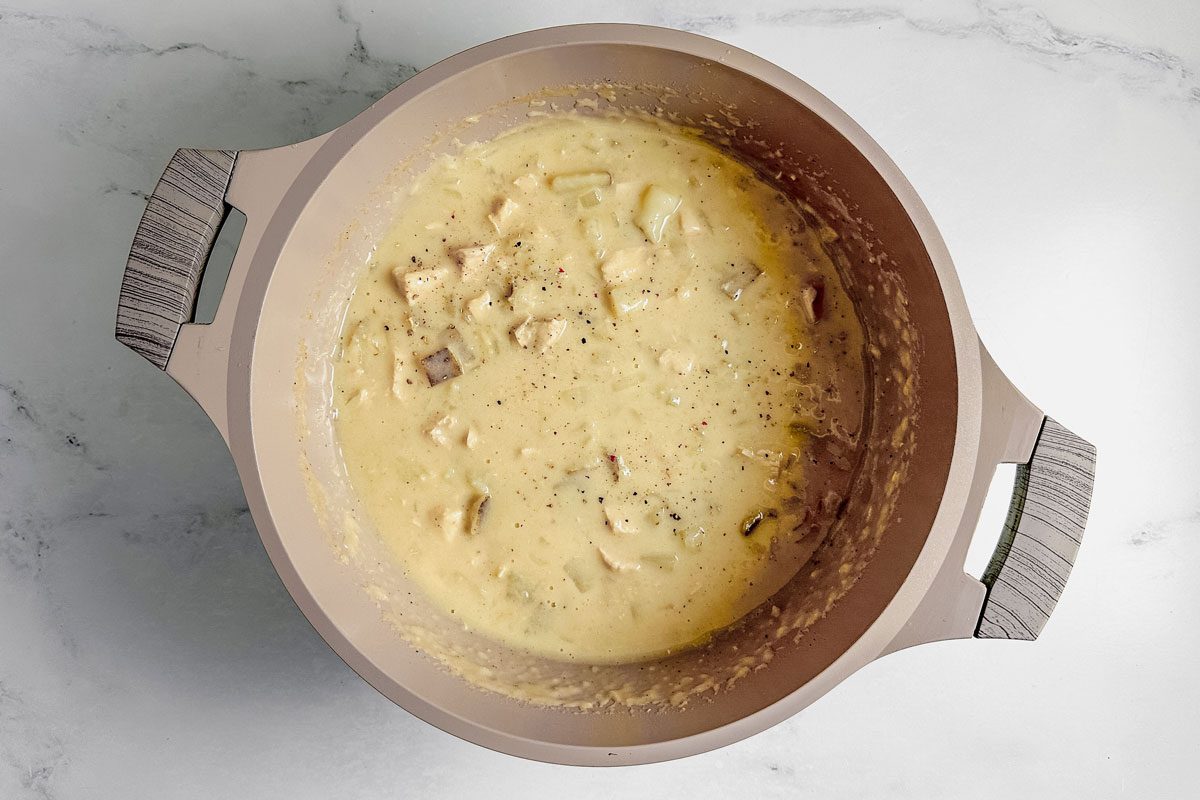Taste of Home chicken potato soup in a Dutch oven on a marble surface.