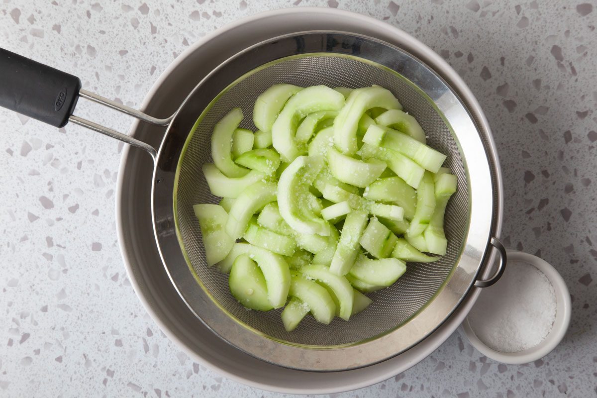 Step 1 of Taste of Home Cucumber Soup is adding salt to the cucumbers and tossing them in a colander