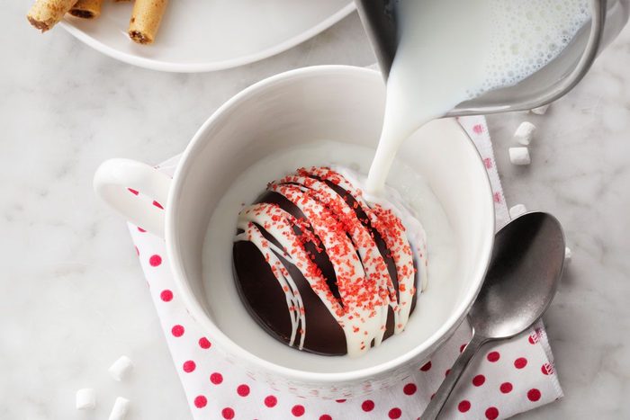 pouring warm milk onto the chocolate bomb