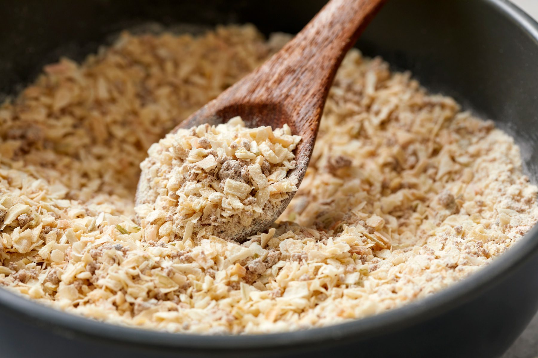 Scooping out onion soup mix with wooden spoon from black bowl