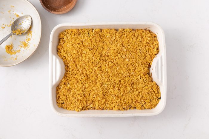 Baking dish with crumbled corn flakes and melted butter mixture on top.