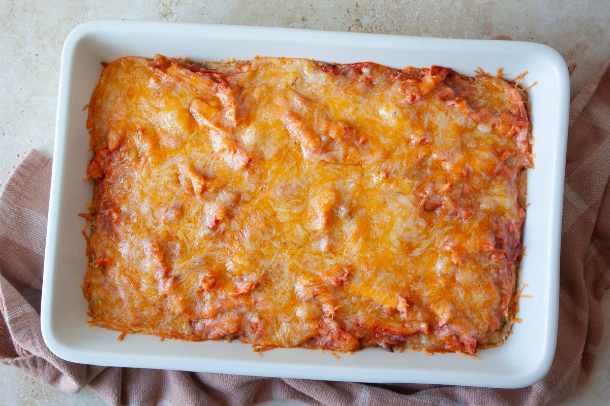 13x9 baking dish with cornbread mixture and topped with shredded chicke, tamale sauce and shredded cheese and baked