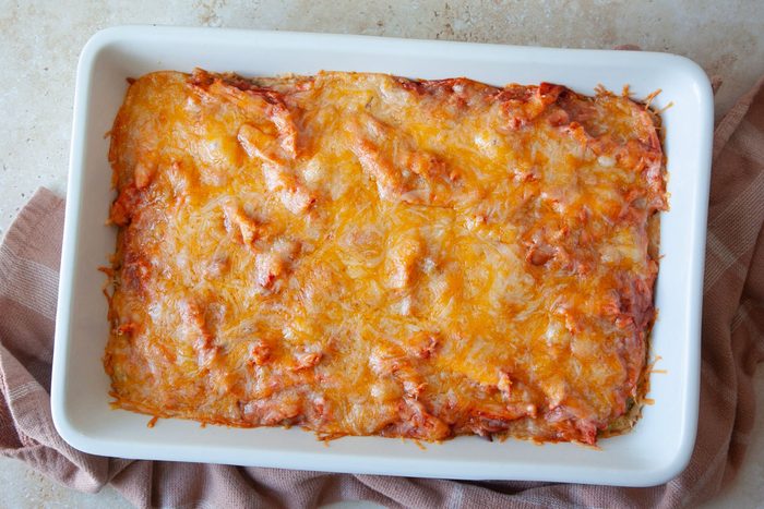 13x9 baking dish with cornbread mixture and topped with shredded chicke, tamale sauce and shredded cheese and baked