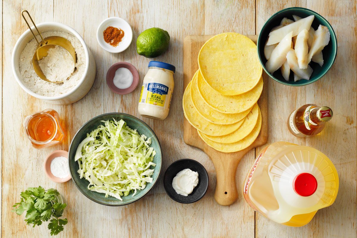 ingredients for Beer Battered Fish Tacos on a light wood background