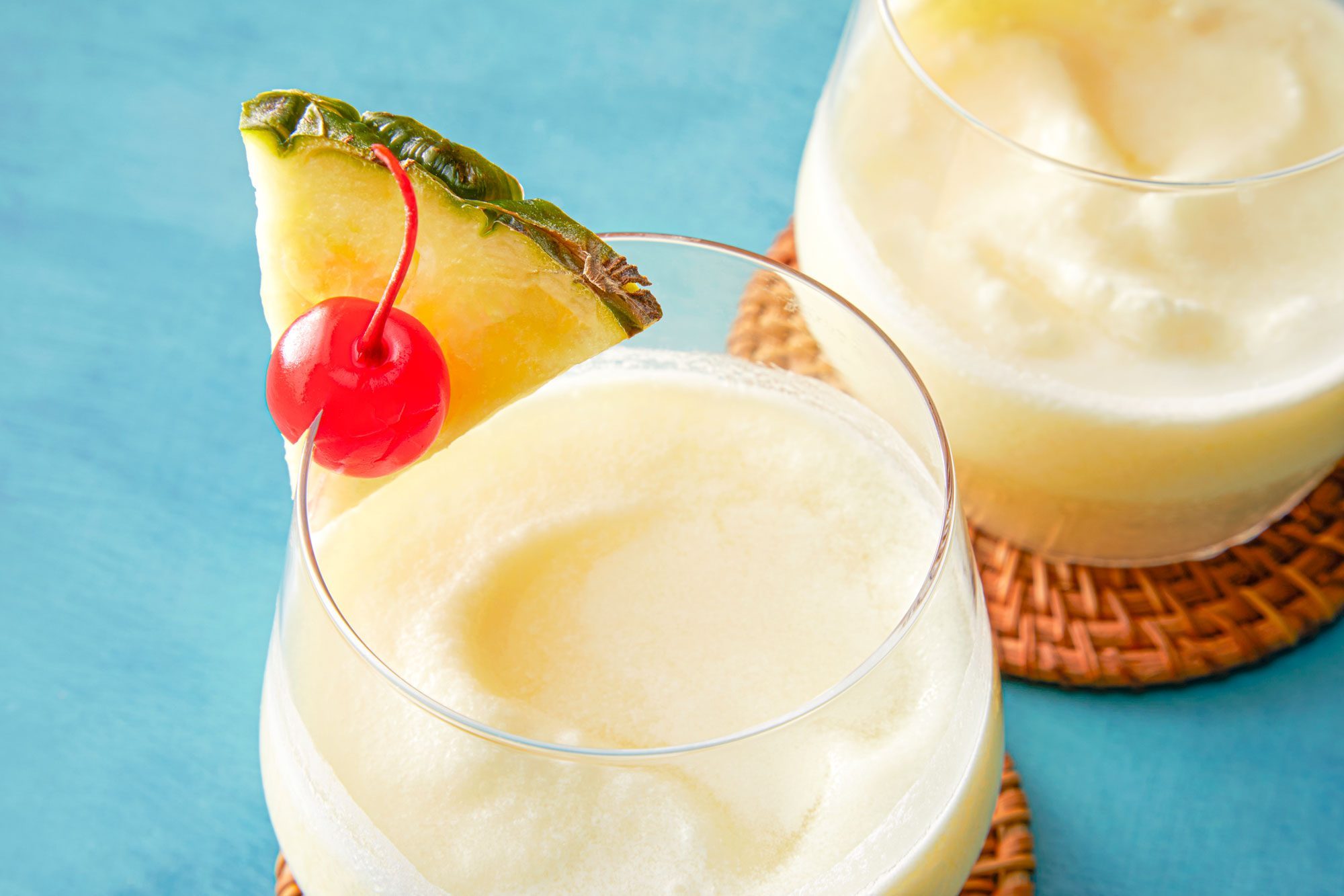 Virgin Pina Coladas in chilled glasses garnished with pineapple and cherry on coasters