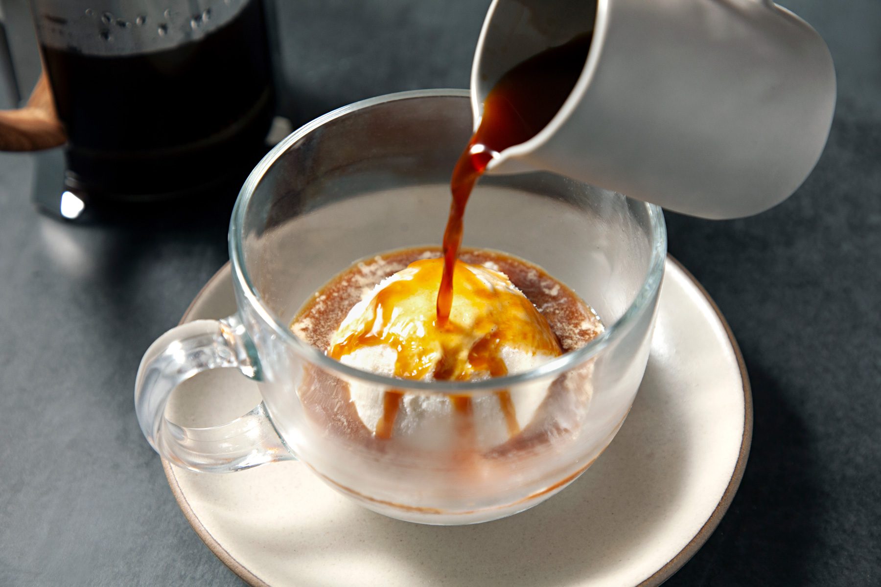 Pouring expresso on top of gelato in a glass cup 