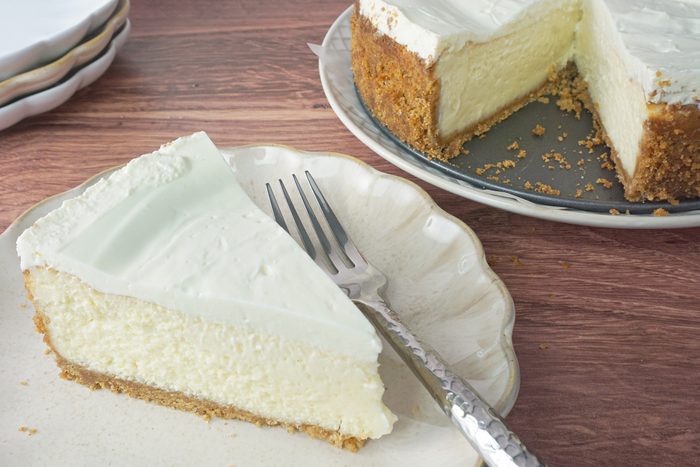 A slice of amaretto cheesecake on a plate near the whole cheesecake RMS 91184 for Taste of Home