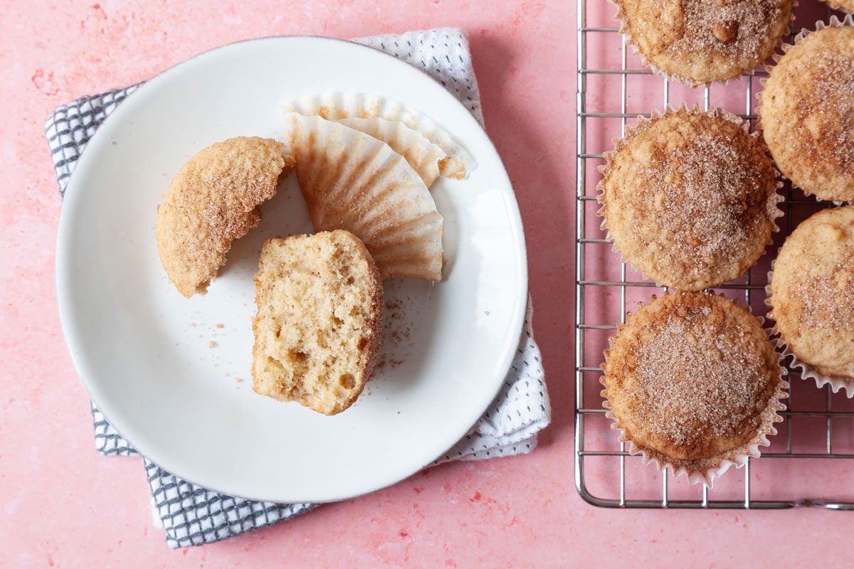Close up of single Taste of Home Applesauce Muffin on plate, cooling rack in the background